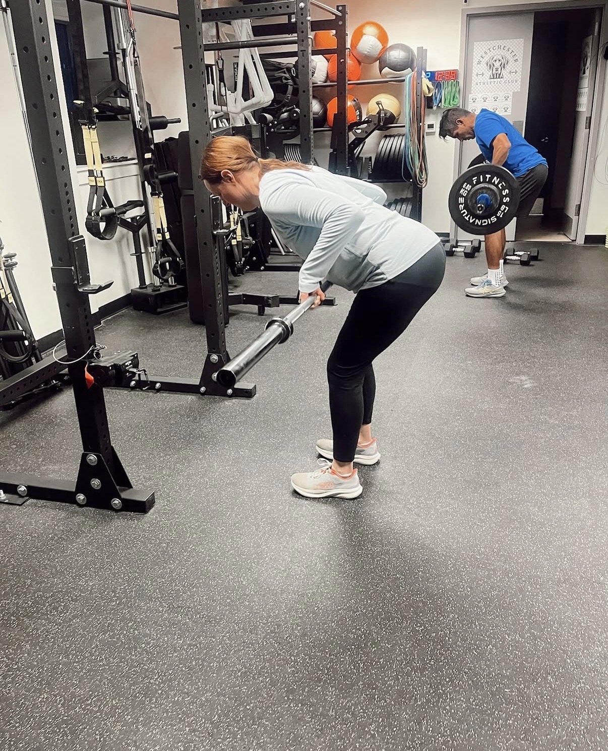 A member practicing barbell hinge and row technique at Westchester Athletic Club