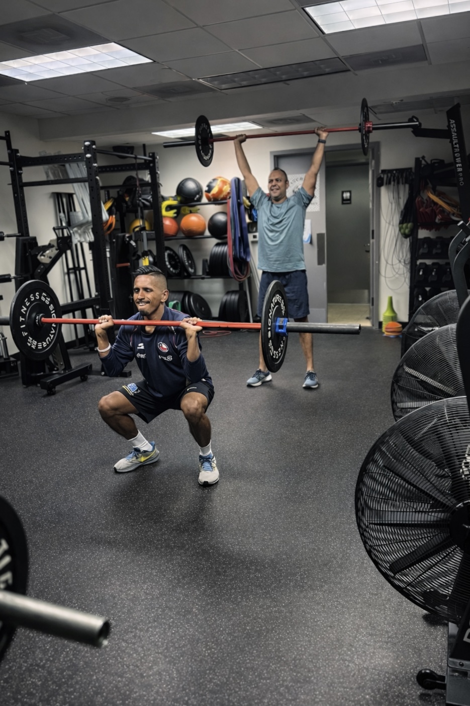 Members training barbell front squats and overhead presses at Westchester Athletic Club